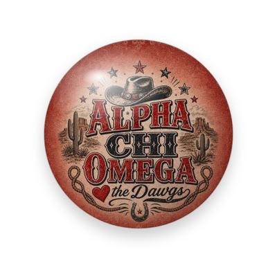 Alpha Chi Omega #061 button. Rusty red desert scene with the full name spelled out in red western letters, a cowboy hat, cacti, stars, a heart, script “the Dawgs”, rope and a horseshoe.