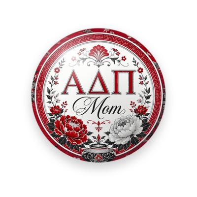 Alpha Delta Pi #054 button. White center with a red Greek key border, red serif Greek letters, black script “Mom”, red and white peonies and a small vase.
