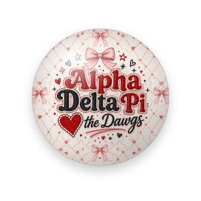 Alpha Delta Pi #067 button. Cream background with a pink trellis pattern and pink bows, the full name spelled out in red and black retro letters, a red heart and black script “the Dawgs.”