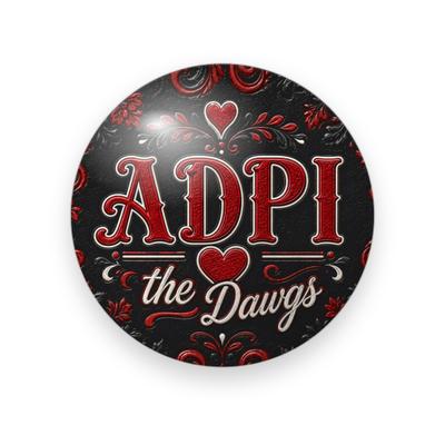 Alpha Delta Pi #072 button. Black background with red flourishes, red serif “ADPI”, a red heart and cream script “the Dawgs.”