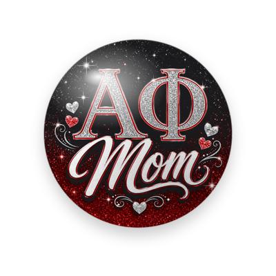 Alpha Phi #070 button. Black starry background fading to red glitter with silver glitter Greek letters, white script “Mom”, and small glitter hearts.