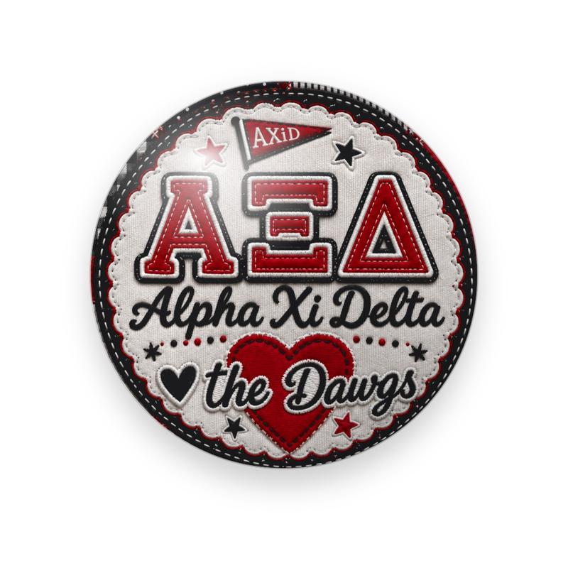 Alpha Xi Delta #023 button. Stitched cream patch with a black and red border, red varsity Greek letters, the full name in black script, a heart, “the Dawgs”, a red “AXiD” pennant, and stars.