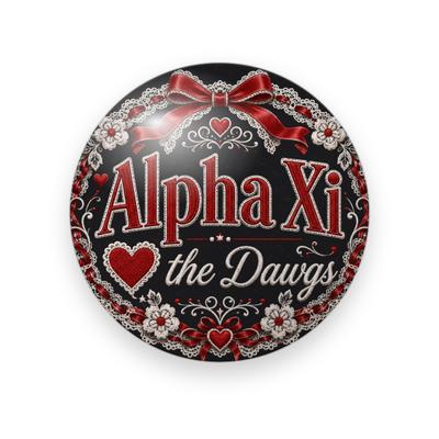 Alpha Xi Delta #052 button. Black background with red serif “Alpha Xi” lettering, white script “the Dawgs”, a red heart, a red satin bow, and white lace flowers.
