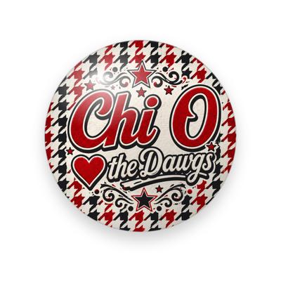 Chi Omega #069 button. Red and black houndstooth behind red “Chi O” script, stars, a red heart, and “the Dawgs” in cream script.
