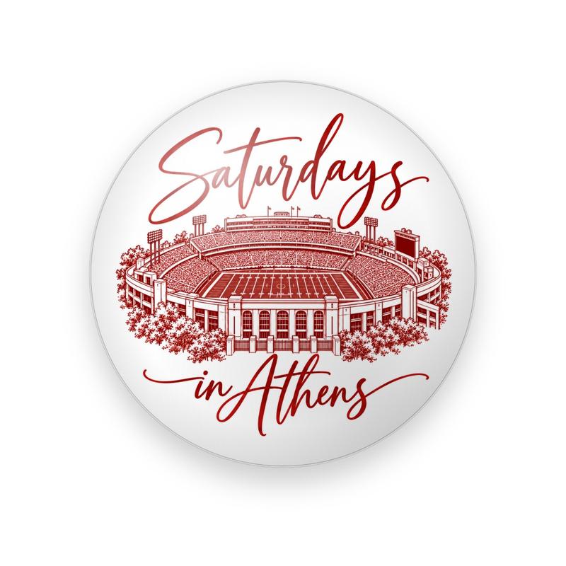 UGA #061 button. White background with a red etched drawing of a packed football stadium between “Saturdays” and “in Athens” in flowing red script.